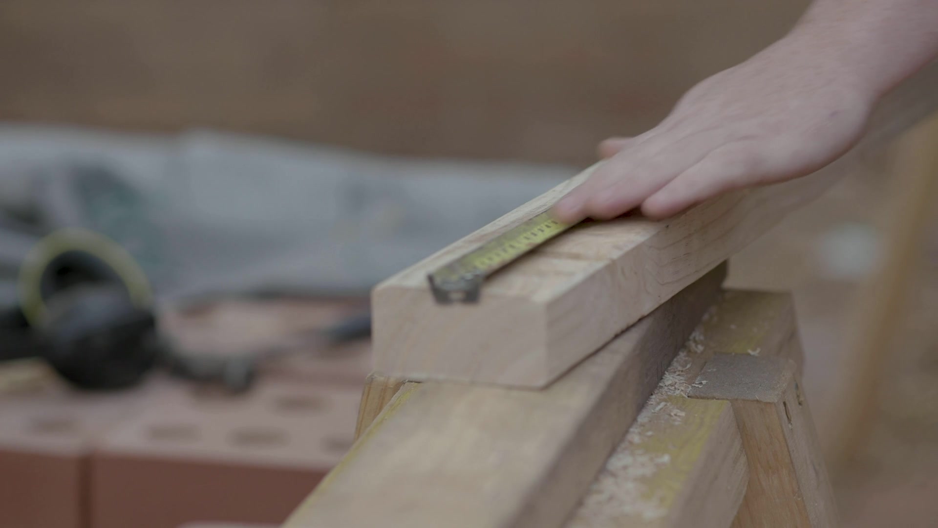 A tradesperson measuring and marking timber at a workbench